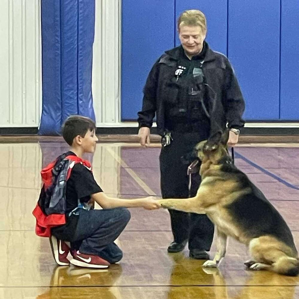 SRO in gym with K9 shaking hands with child